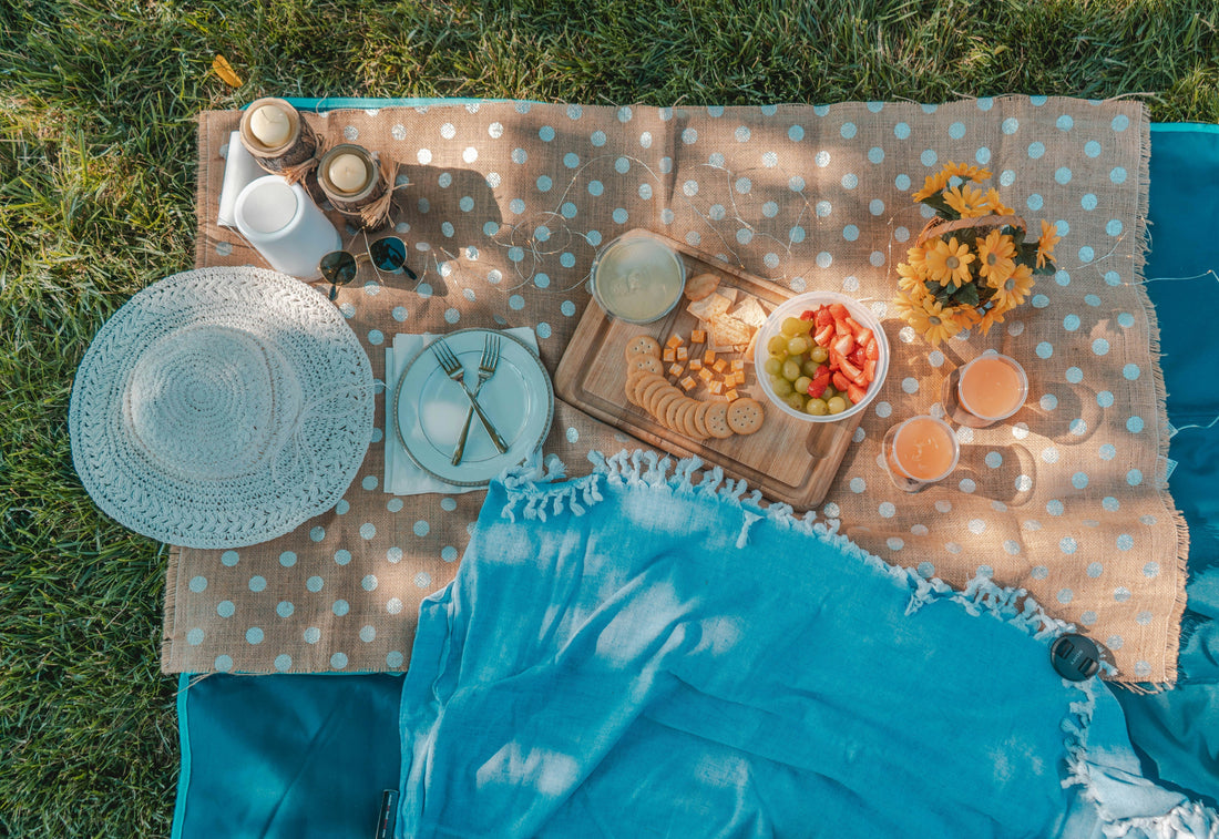 Nappe de pique-nique étalée sur l'herbe : accessoires zéro déchet et choses à picorer